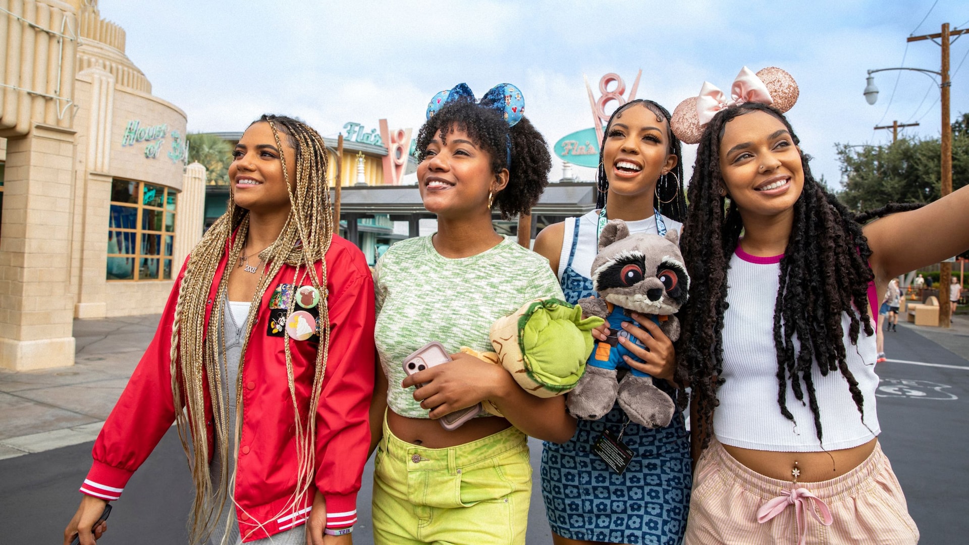 Four young women smiling as they walk through Cars Land